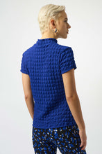 Load image into Gallery viewer, Person wearing a blue textured top and patterned pants against white background.