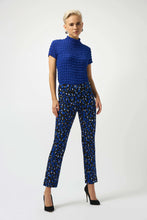 Load image into Gallery viewer, Woman wearing a blue textured top, patterned pants and heels against a white background.