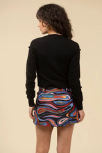 Load image into Gallery viewer, Woman wearing a black sweater and mini skort in abstract pattern against a light beige background.