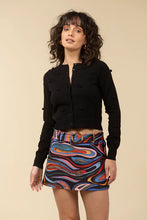 Load image into Gallery viewer, Woman wearing a black sweater and mini skort in abstract pattern against a light beige background.