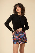 Load image into Gallery viewer, Woman wearing a black cardigan and mini skort in abstract pattern against a light beige background.