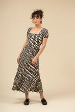 Load image into Gallery viewer, Woman wearing a brown and white polka dot dress and brown loafers against a beige background.