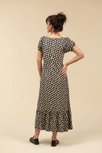 Load image into Gallery viewer, Woman wearing a brown and white polka dot dress and brown loafers against a beige background.