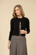 Load image into Gallery viewer, Woman wearing a black cardigan over a checkered dress against a beige background.