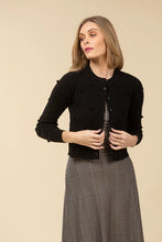 Load image into Gallery viewer, Woman wearing a black cardigan over a plaid dress against a beige background.