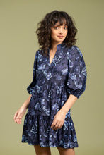 Load image into Gallery viewer, Woman wearing a blue and navy floral dress against a pale green background.