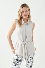 Load image into Gallery viewer, The fabrication used to create this gorgeous top by Joseph Ribkoff is absolutely amazing. The flowy texture and lightweight feel make it an ideal top for summer styling. A timeless design which includes button down with a fabric that softly drapes and then can be tied in the middle. Color- Moonstone. Self-tie. Button down. Sleeveless. No pockets. Not lined. Fabric - 100% Polyester.