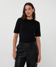 Load image into Gallery viewer, Woman wearing a black short-sleeve top with black sequins and black leather pants against a white background.