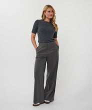 Load image into Gallery viewer, Woman wearing a dark gray sequin ribbed short-sleeve top, gray pinstripe pants and white sneakers against a white background.