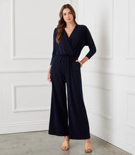 Load image into Gallery viewer, Our best-selling jumpsuit is now available in a beautiful navy color! Crafted from a high-quality, wrinkle-resistant jersey fabric, this jumpsuit is as low-maintenance as it is chic. Designed for the modern jetsetter, this jumpsuit combines comfort, style, and practicality for a seamless travel experience.