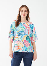 Load image into Gallery viewer, Experience a touch of tropical charm with this FDJ French Dressing three-quarter sleeve raglan top, featuring a vibrant print that effortlessly adds a playful and stylish flair to any wardrobe. Color- Tropical; vivid blues, pink, green, yellow, orange and white. Boat neckline. Wide sleeves. Local artist print. Length 25".