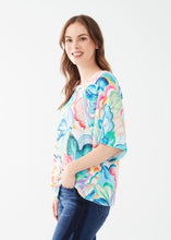 Load image into Gallery viewer, Experience a touch of tropical charm with this FDJ French Dressing three-quarter sleeve raglan top, featuring a vibrant print that effortlessly adds a playful and stylish flair to any wardrobe. Color- Tropical; vivid blues, pink, green, yellow, orange and white. Boat neckline. Wide sleeves. Local artist print. Length 25".
