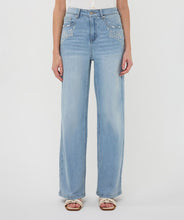 Load image into Gallery viewer, Close-up of model wearing blue jeans with embroidery and natural sandals against a white background.