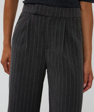 Load image into Gallery viewer, Close-up of dark gray pinstripe pants worn by a model against a light gray background.