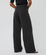 Load image into Gallery viewer, Model wearing black pinstripe pants, black short sleeve top and white and black sneakers against a white background.