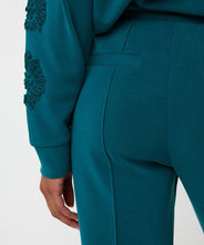 Load image into Gallery viewer, Close-up of teal modal pants and teal embroidered sleeve on sweater against a white background.