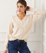 Load image into Gallery viewer, Woman wearing a beige cardigan, blue jeans, heart necklace and black belt against a white wall.