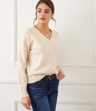 Load image into Gallery viewer, Woman wearing a beige cardigan, blue jeans, heart necklace and black belt against a white wall.