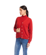 Load image into Gallery viewer, Woman wearing a red cardigan over a coordinating turtleneck and blue jeans against a white wall.