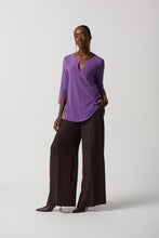 Load image into Gallery viewer, This stunning tunic designed by Joseph Ribkoff offers a graceful fit and an eye-catching look, with a vivid violet hue and a silver-ring keyhole detail on both the front and the back. Its effortless style ensures that it will be a statement piece in your wardrobe. Color- Violet. Tunic length. Keyhole design. Silver ring hardware in front and back. Fabric- 96% Polyester. 4% Spandex.