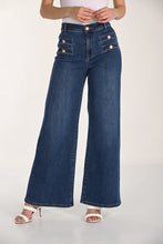 Load image into Gallery viewer, Model wearing wide-leg jeans with button details and white sandals against a white background.