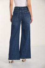 Load image into Gallery viewer, Model wearing wide-leg jeans with button details and white sandals against a white background.