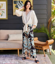 Load image into Gallery viewer, Step into effortless sophistication with the Wryn Wide Leg Pants in Damask Floral Print by Karen Kane. These elegant pants feature a stunning damask floral design in soft brown and blue hues, adding a touch of refinement to your wardrobe. The wide-leg silhouette creates a flattering and modern look, while the elasticized waist and convenient side pockets ensure practicality without compromising elegance.
