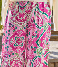 Load image into Gallery viewer, The Wyndy Wide Leg Pants in Pink and Green Multicolor Print by Karen Kane are stylish wide-leg pants featuring a striking Italian tile border print on smooth crepe fabric. They are fitted at the waist and relaxed at the hips, offering a comfortable drape with a pull-on elastic waistband and functional side pockets. Ideal for pairing with solid tops or matching prints, these wide-leg pants can be dressed up with heels or kept casual with sandals.