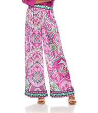 Load image into Gallery viewer, The Wyndy Wide Leg Pants in Pink and Green Multicolor Print by Karen Kane are stylish wide-leg pants featuring a striking Italian tile border print on smooth crepe fabric. They are fitted at the waist and relaxed at the hips, offering a comfortable drape with a pull-on elastic waistband and functional side pockets. Ideal for pairing with solid tops or matching prints, these wide-leg pants can be dressed up with heels or kept casual with sandals.