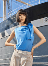 Load image into Gallery viewer, The Zulena Bow-Tie Neck Top in vibrant Electric Blue is a true wardrobe essential for fashion-forward individuals. Designed with a straight, cropped fit that runs true to size, this sleeveless top is crafted from luxurious Soft Touch Satin for a smooth, elegant feel. Cut on the bias for a flattering drape, it features stylish details such as a diagonal back seam, chic side slits, and an adjustable shoulder tie, making it the perfect blend of comfort and sophistication.