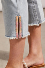 Load image into Gallery viewer, ur Silvia is a super stylish and undeniably comfortable straight-leg jean with a mid-rise fit. The stand-out feature are the side slits at the hem emphasized with embroidered light orange and bright pink detailing. A perfect jean that goes with so many tops including our Farah Flutter Sleeve Textured Blouse with Tassels by Tribal (pictured) Color - Coastline; Light blue. Side slits with embroidery in light orange and bright pink. Mid-rise. Zipper and button closure. Functional front and back pockets.