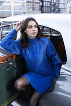 Load image into Gallery viewer, A piercing bright blue color dazzles on this mesmerizing Bettina dress. The classic cable pattern and ribbed cuffs, along with a slightly oversized fit, creates a style that will become your next fashion favorite. Our Bettina is a beautiful piece to style with leggings and boots or choose to wear alone with boots or heels. Color- Blue. Pull-over style. Mock-neck. Ribbed cuffs.