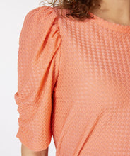 Load image into Gallery viewer, Our Brittany short sleeve top in a brilliant bright peach color will become your next wardrobe favorite. Designed with just the right amount of ruffle sleeve to create a fashionable look, the Brittany includes a beautiful textured fabric. This top pairs with almost any bottom, and looks stunning when worn with our GLORIA GROOVY PRINT WIDE LEG PANT - ESQUALO. Color- Bright peach. Pull-over. Ruffle sleeve design. Textured fabric. Short-sleeve. Stretch fabrication. Slightly sheer.