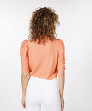 Load image into Gallery viewer, Our Brittany short sleeve top in a brilliant bright peach color will become your next wardrobe favorite. Designed with just the right amount of ruffle sleeve to create a fashionable look, the Brittany includes a beautiful textured fabric. This top pairs with almost any bottom, and looks stunning when worn with our GLORIA GROOVY PRINT WIDE LEG PANT - ESQUALO. Color- Bright peach. Pull-over. Ruffle sleeve design. Textured fabric. Short-sleeve. Stretch fabrication. Slightly sheer.
