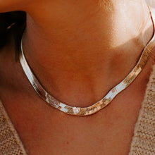 Load image into Gallery viewer, Our Capulet Gold Herringbone and Heart Necklace is absolutely stunning! This special necklace is 7 mm of liquid gold with a 5mm cubic zirconia heart set in the middle of the herringbone. Pair it with our Capulet Gold Herringbone and Heart Bracelet and Capulet Gold Herringbone and Heart Ring for the complete brilliant look.