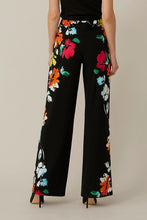 Load image into Gallery viewer, The Nalini floral pants from Joseph Ribkoff epitomize both comfort and style. Adorned with a vivid and lively floral design, these wide-leg pants are bound to garner admiration. The Nova features an easy pull-on design and an elastic waistband for supreme comfort. Its smooth, silky knit material offers a touch of luxury.