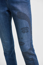Load image into Gallery viewer, Inspired by the 60's model Twiggy, the Brielle Jean with Sparkle Face Design is truly a work of art that you can wear. This beautiful and comfortable ankle length, classic slim blue jean has a partial female face design on the left leg created with a series of gorgeous sparkling black crystals. You will definitely receive numerous compliments when you wear this work of art. Color- Blue with black crystals.