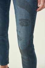 Load image into Gallery viewer, Inspired by the 60's model Twiggy, the Brielle Jean with Sparkle Face Design is truly a work of art that you can wear. This beautiful and comfortable ankle length, classic slim blue jean has a partial female face design on the left leg created with a series of gorgeous sparkling black crystals. You will definitely receive numerous compliments when you wear this work of art. Color- Blue with black crystals.