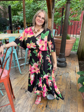 Load image into Gallery viewer, The Ellie Woven Maxi Dress is so stunning with a black background and a floral print that just pops! This gorgeous style features a surplice neckline and is a true wrap design with a ruffled hemline. A dress for those perfect moments in your life.