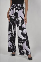Load image into Gallery viewer, Make a bold fashion statement with the Frank Lyman Abstract Print Palazzo Pant, featuring a striking lavender and black abstract pattern. Designed for both comfort and elegance, this high-waisted, wide-leg pant offers a flattering silhouette with a belted jersey knit fabric that provides the perfect amount of stretch. The easy pull-on style ensures effortless wear, while the unlined construction keeps it lightweight and breathable.