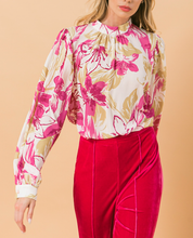 Load image into Gallery viewer, Our Ashley floral blouse is both sophisticated and fun! A stunning abstract floral print in pink and taupe on a white base gives this blouse an edge, while billowy sleeves offer a feminine appeal. Gathering at the collar, sleeves and shoulders add that extra flair. Effortlessly pair this blouse with jeans for a casual look or dress up with your favorite bottoms.
