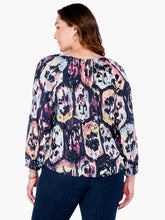Load image into Gallery viewer, A striking vintage pattern creates an eye-appealing design on this flowy peasant shirt silhouette. Modern details like an elastic cuff and smock detailing ad even more beauty to this gorgeous top. The fabric used to create our Misty has been mindfully made from EcoVero rayon that uses sustainable material and less water. Color-Indigo Mix- Navy, light blue, coral, tan, white, yellow, purple. Woven top. Relaxed fit. Split neck. 3/4 sleeve. Basic sleeve. Tie front. Sits at hip.