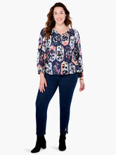 Load image into Gallery viewer, A striking vintage pattern creates an eye-appealing design on this flowy peasant shirt silhouette. Modern details like an elastic cuff and smock detailing ad even more beauty to this gorgeous top. The fabric used to create our Misty has been mindfully made from EcoVero rayon that uses sustainable material and less water. Color-Indigo Mix- Navy, light blue, coral, tan, white, yellow, purple. Woven top. Relaxed fit. Split neck. 3/4 sleeve. Basic sleeve. Tie front. Sits at hip.