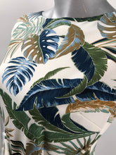Load image into Gallery viewer, An absolutely gorgeous dress, our Winslow White Tropical dress drapes beautifully and is figure flattering. A white background comes alive with a tropical fern print and is enhanced with a gorgeous, attached tie that can be tied in the front or back. Worn to lunch or a night out. This gorgeous summer dress will make a fashion statement.
