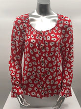 Load image into Gallery viewer, Small white flowers with black centers just pop on this gorgeous true red long sleeve top. The feminine touches create a romantic top with a scoop neckline and a row of button closures, as well as ruffled cuffs. A lightweight material, this will keep you cool in the warmer days and warm when there is a slight chill. This is the choice of top to pair with crisp white bottoms and effortlessly goes well with jeans.