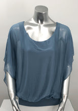 Load image into Gallery viewer, A free-flowing fabrication creates a stunning top in a slate blue color. Top is lined with a knit covered by a gorgeous silk. Bottom is banded in the same color. Create a classy and fashion forward look with our Darla by pairing it with our M Made in Italy silk bottoms. Color- Slate blue. Knit lining slate blue. Flowy fabrication on the outside. A knit lining on the inside prevents see through. Banded bottom.