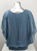 Load image into Gallery viewer, A free-flowing fabrication creates a stunning top in a slate blue color. Top is lined with a knit covered by a gorgeous silk. Bottom is banded in the same color. Create a classy and fashion forward look with our Darla by pairing it with our M Made in Italy silk bottoms. Color- Slate blue. Knit lining slate blue. Flowy fabrication on the outside. A knit lining on the inside prevents see through. Banded bottom.