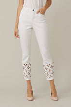 Load image into Gallery viewer, This slim leg capri designed by Joseph Ribkoff has a style that is not only unique but highly fashionable. The floral cut-out pattern at the cuff of each leg is enhanced by sparkling crystals that catch the eye! A slight fray at the bottom of each leg gives this spectacular jean an edge. The Isla is not only elegant but also fun at the same time. A pure white jean, this capri will pair beautifully with anything in your closet!