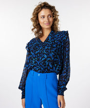 Load image into Gallery viewer, A gorgeous pop of all over blue in an animal print is striking on the Wilda Wild Celebration Blouse. The Wilda has a round neckline, decorative ruffles on the shoulders and smocked cuffs. Pair with a pair of faux leather or black pants or your favorite denim and boots and you'll be a fashionista!