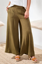 Load image into Gallery viewer, Model wearing olive green wide-leg pants with a white top and brown sandals on a neutral background.

